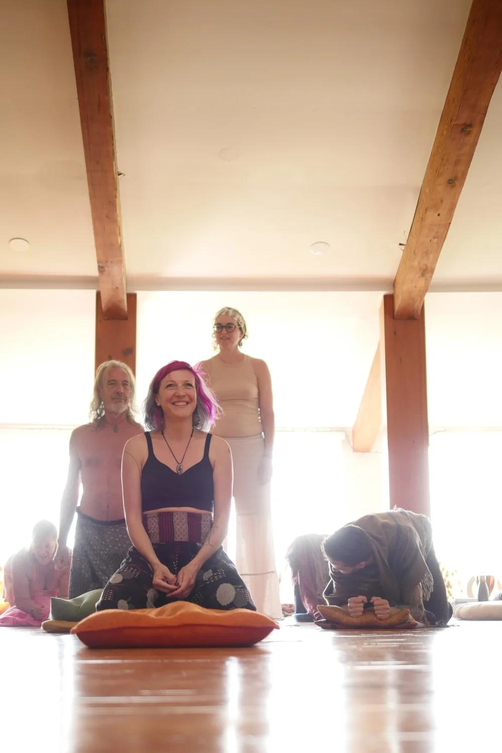 Un groupe en séance de yoga ou de méditation dans une pièce lumineuse.